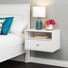 White night stand with a lamp and books in a modern bedroom.