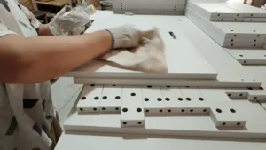 Worker cleaning and inspecting the front, back and edges of furniture panels at an OEM panel furniture factory