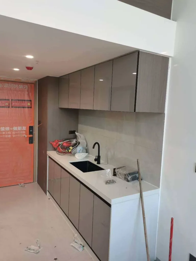 Modern straight-line apartment kitchen cabinets with gray flat-panel doors and white quartz countertop