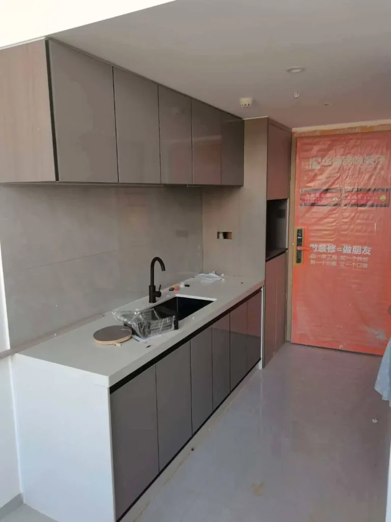 Straight-line OEM kitchen cabinet installation with glossy gray doors and integrated sink